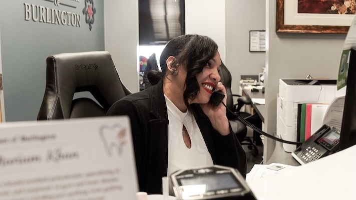 Receptionist talking on her desk at Dental Care of Burlington