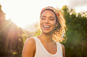 Black woman smiling in the sun after appointment at Dental Care of Burlington in Burlington, MA