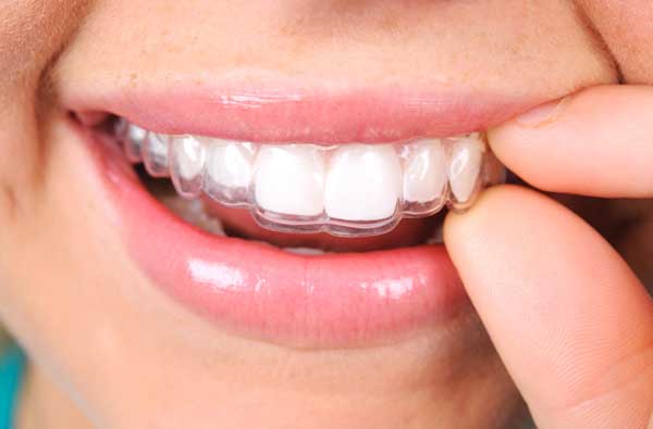 Woman using Invisalign® clear aligner at Dental Care of Burlington in Burlington, MA