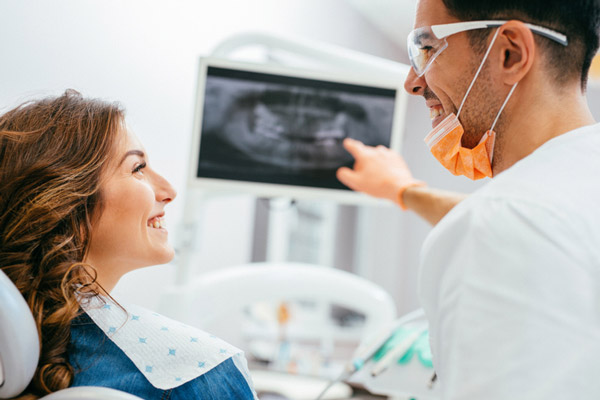 Patient smiling with dentist before oral surgery at Dental Care of Burlington in Burlington, MA